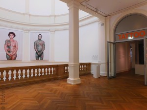 Vue de l'entrée de l'exposition avec deux portraits de personnes tatouées extraites de la série "Why I love tattoos" de Ralph Mitsch