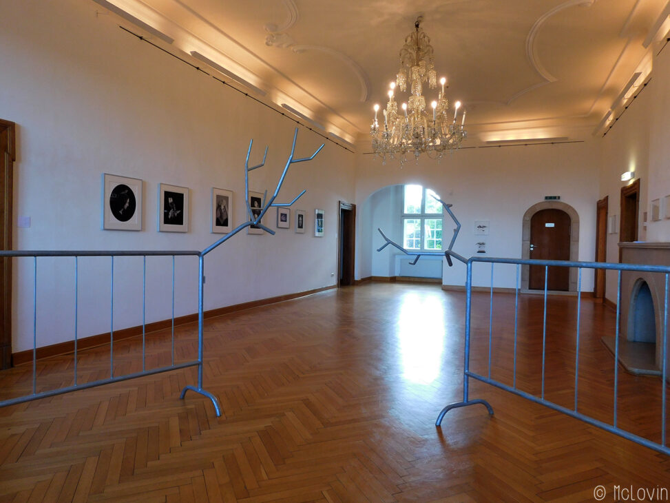 Grande salle centrale de l'exposition avec les "barrières" Paradise Now 1 + Now 4 de Krištof Kintera et à gauche la série de photos sans titre de Juul Kraijer.