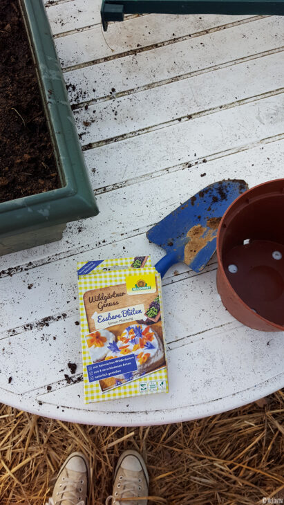 Le paquet de graines de fleurs comestibles Neudorff et le matériel pour les semer / planter dans la jardinière de la serre.