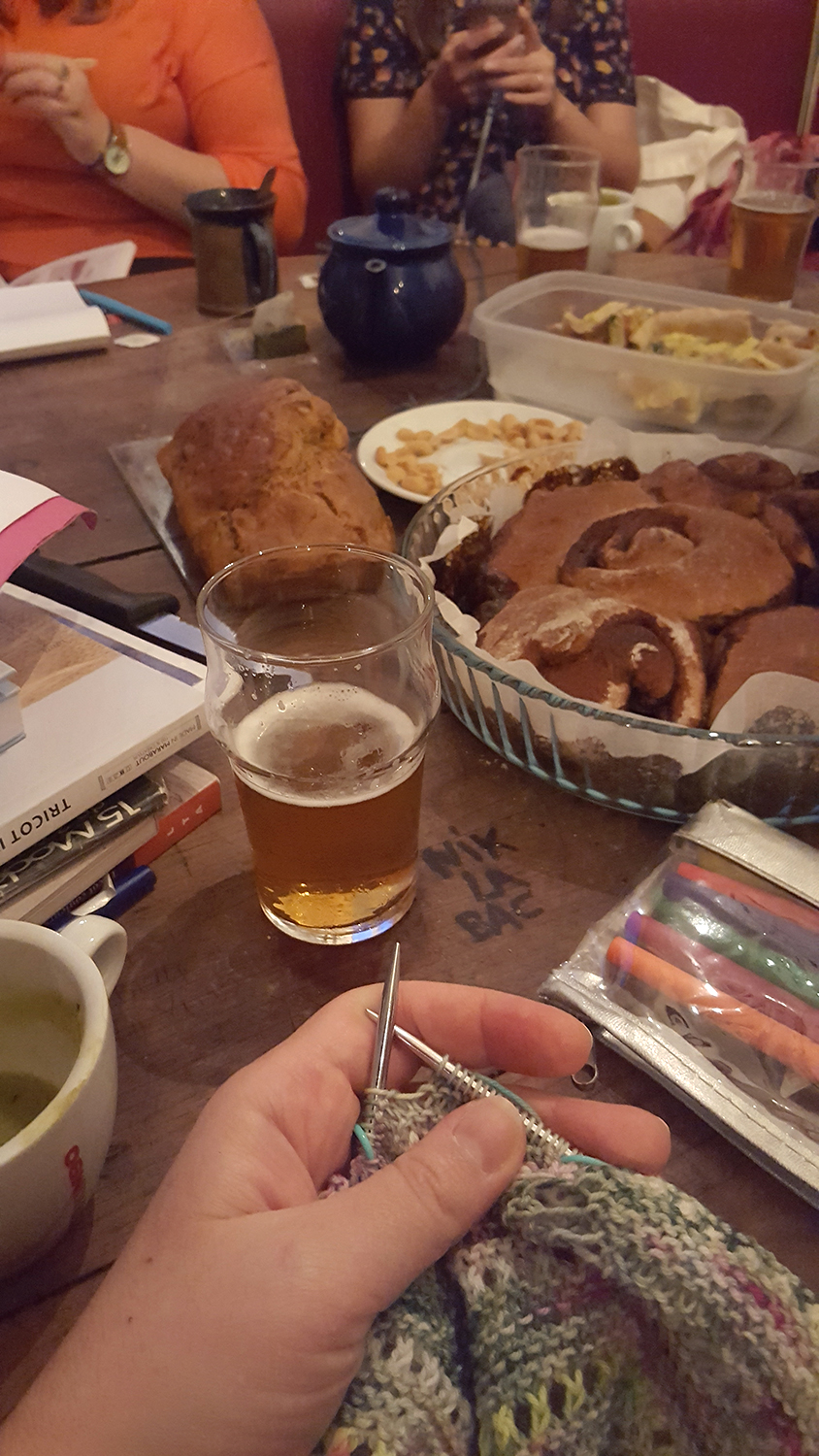 Une vue de l'apéro-tricot au bar librairie le Papier Timbré à Rennes avec du tricot, de la bière ou du thé ou autres, un peu à manger (brioche, cake, tartes, chips...).