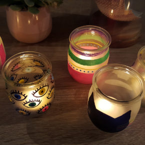 Plusieurs photophores décorés avec des marqueurs Posca éclairés avec une bougie pour créer une lumière douce et un éclairage tamisé.