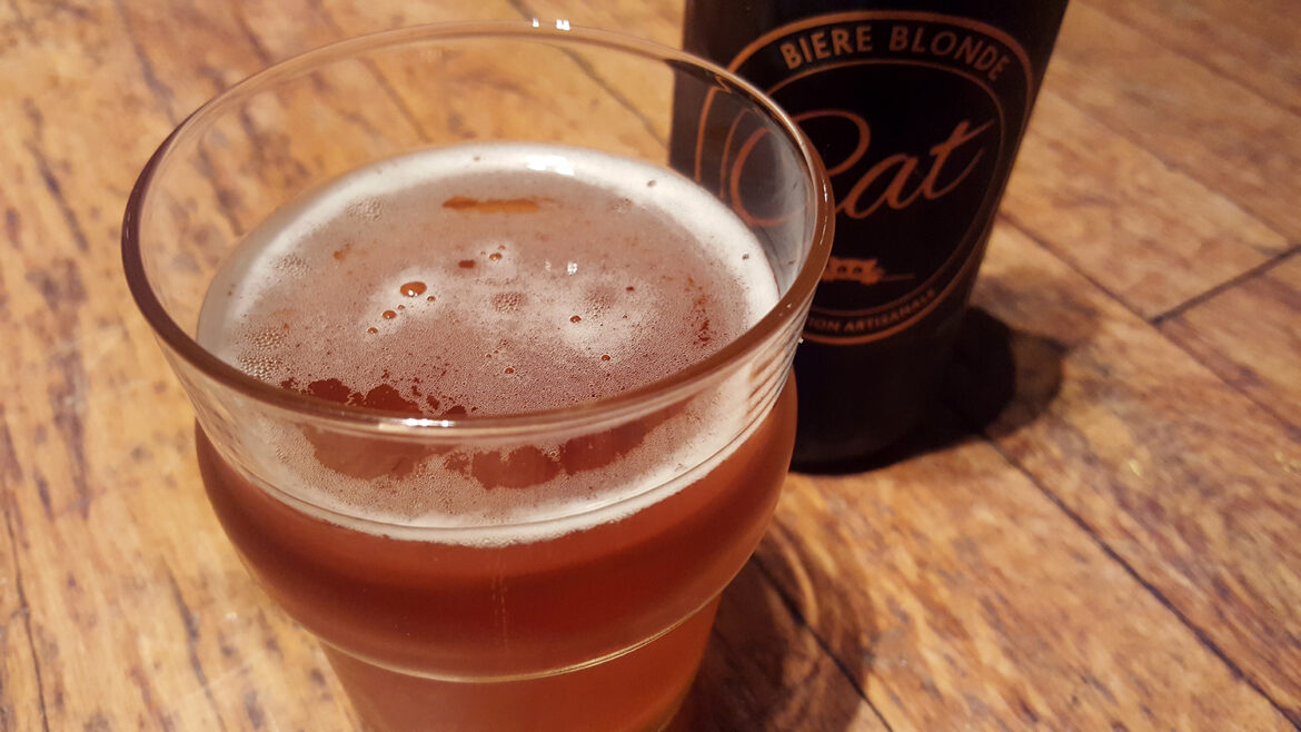 Un verre de bière blonde artisanale Cat à côté de la bouteille avec son super logo doré représentant un chat.