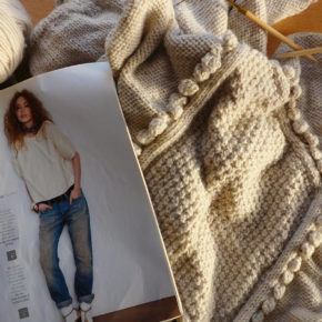 Mon pull gris à noppes Phildar en cours de tricot avec le catalogue de modèles et la laine Katia Merino Aran.