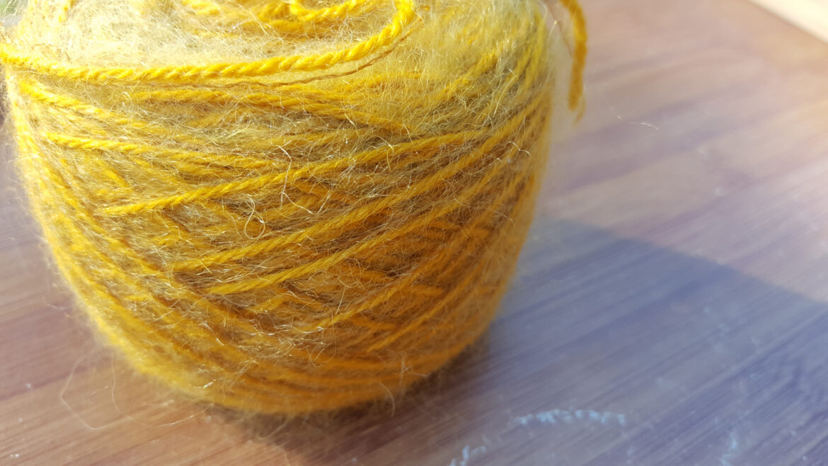 Pelote de laine alpaga (100% alpaga) et plumette (mélange mohair polyamide) de La Droguerie en coloris jaune utilisée pour tricoter le châle Rue de Grenelle de La Droguerie