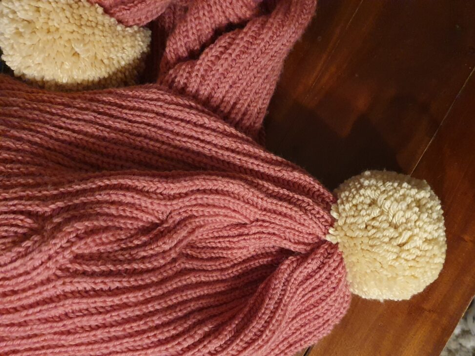 Ma grosse écharpe vieux rose avec ses énormes pompons crème tricotée main avec une torsade de côtes anglaises de haut.