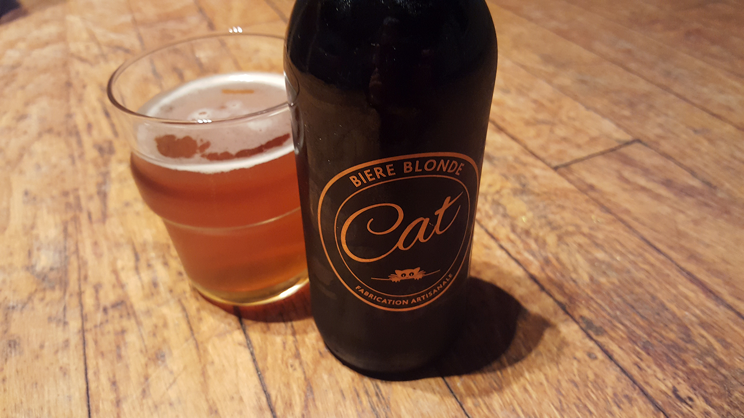 La bouteille de bière blonde artisanale Cat et son super logo doré représentant un chat à côté d'un verre servi.